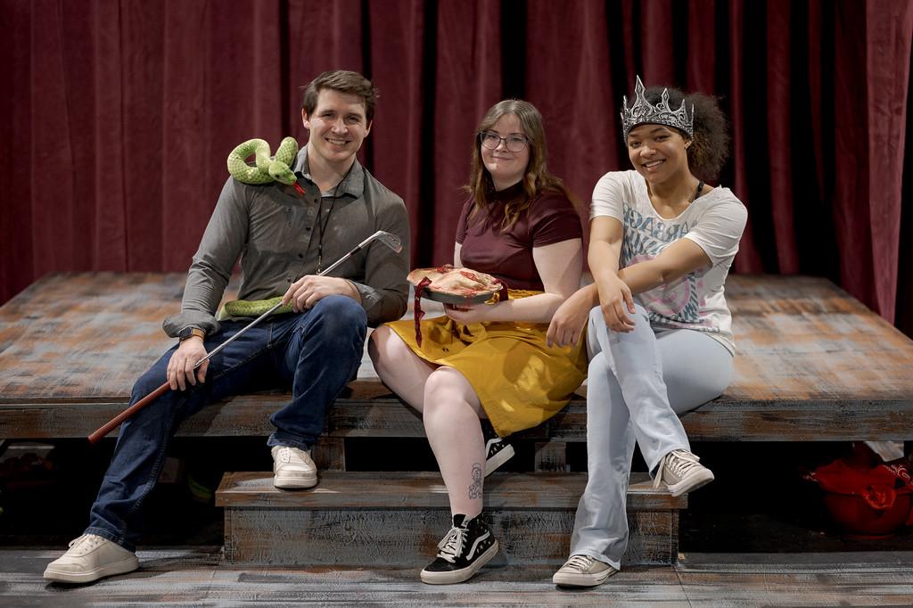 Three actors seated on a stage